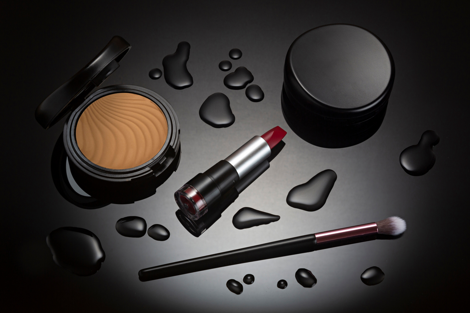 Makeup lipstick and cosmetics on black background with spot lighting.
